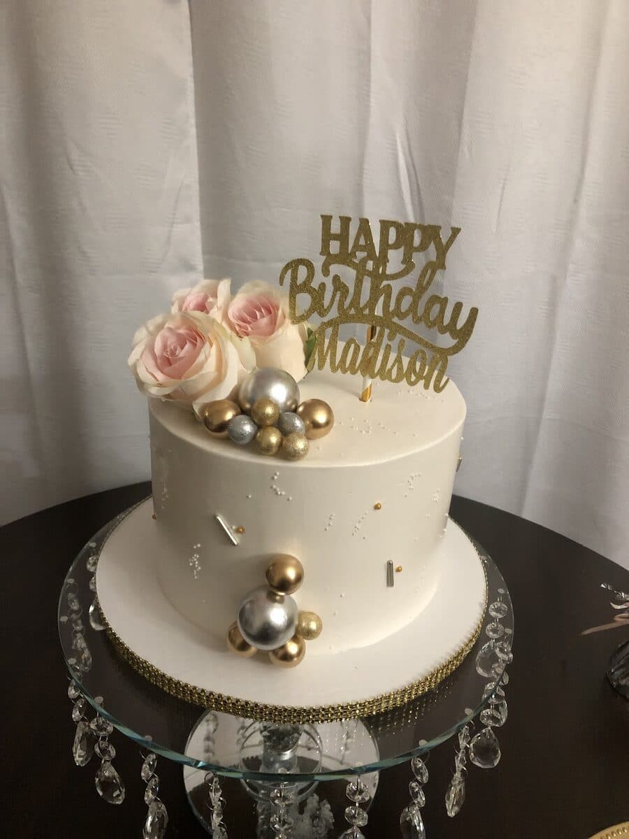 White and gold birthday cake with sugar pearls on a chandelier stand